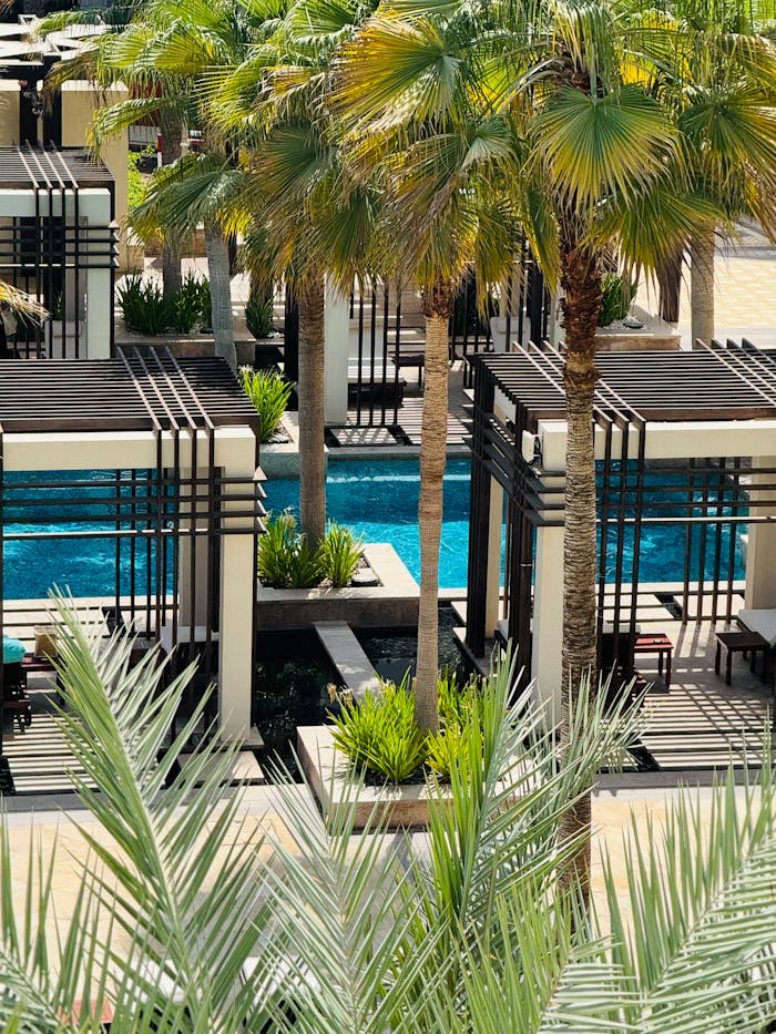 Elegant poolside cabanas surrounded by palm trees in a luxury Oman resort, perfect for relaxation.